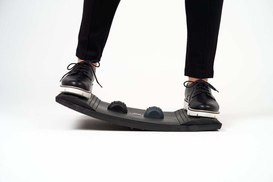 Gymba balance board in use, front view showing ergonomic balance board with active standing foot placement for workplace movement.