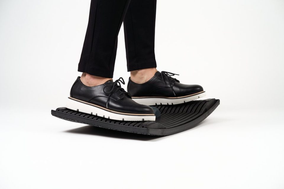 Gymba balance board in use under desk, ergonomic standing footrest supporting active movement and balance while working.