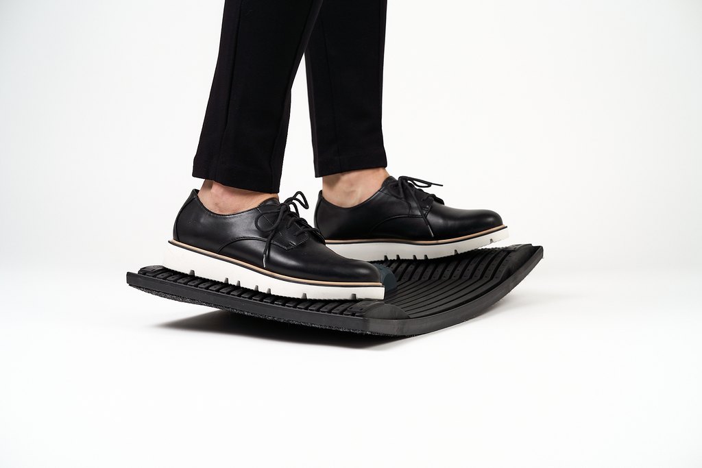 Gymba balance board in use under desk, ergonomic standing footrest supporting active movement and balance while working.