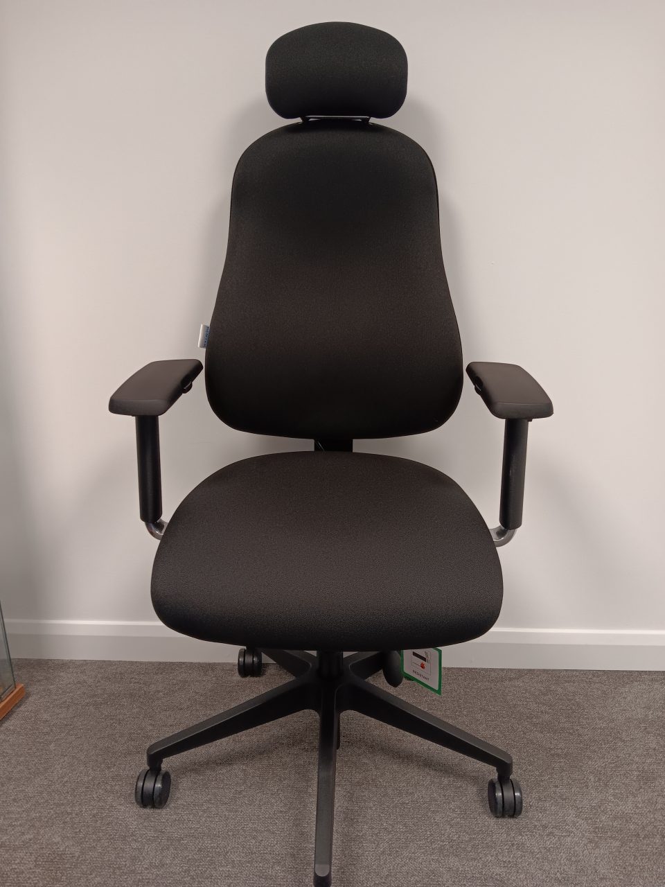 Front view of an RS74 ergonomic office chair in black fabric with adjustable headrest, contoured backrest, height adjustable armrests, and five star base on castors.