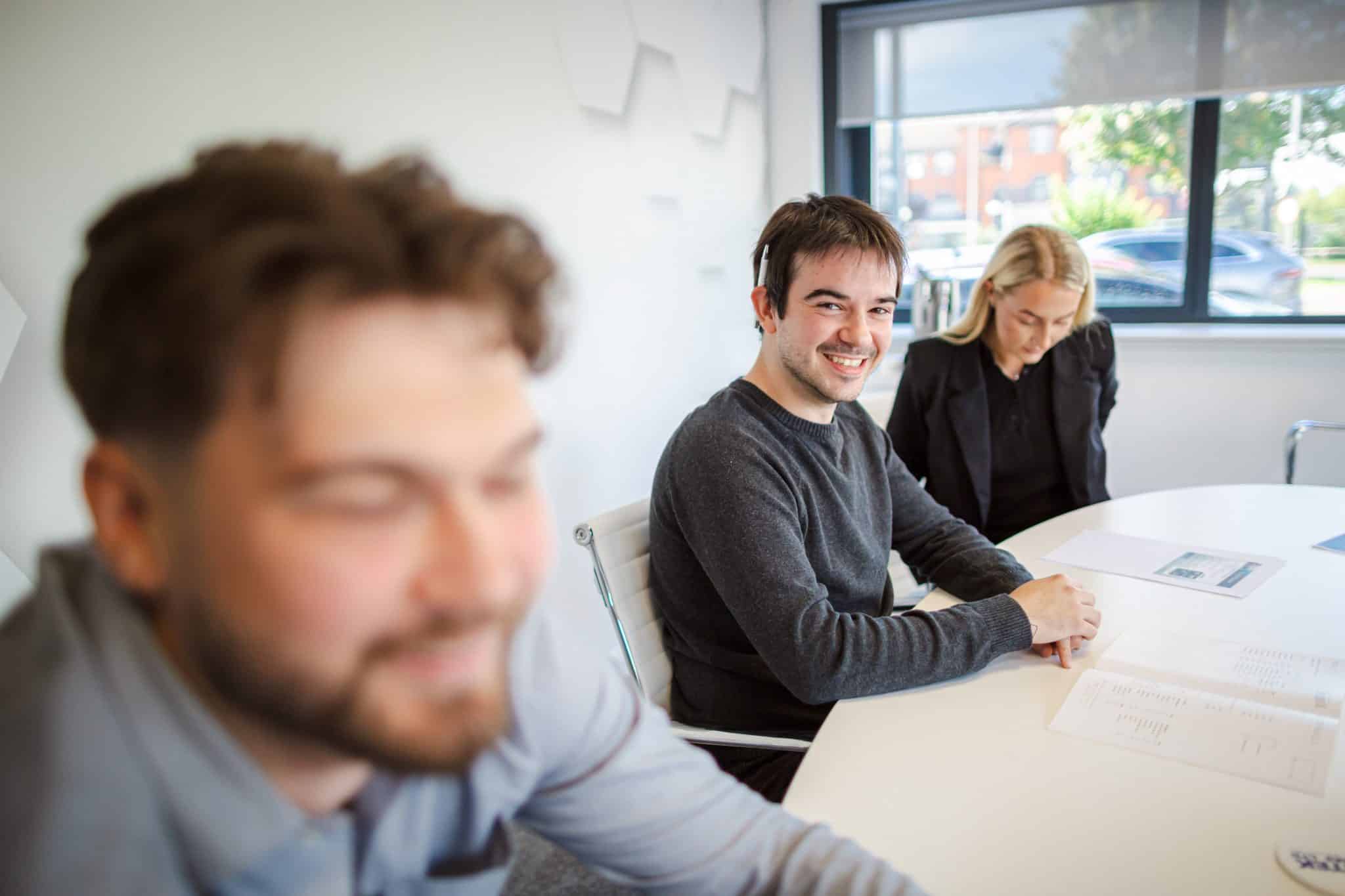 Neurodiversity awareness session showing colleagues engaged in a supportive workplace discussion, demonstrating inclusive communication, active listening, and positive team interaction in a modern office.