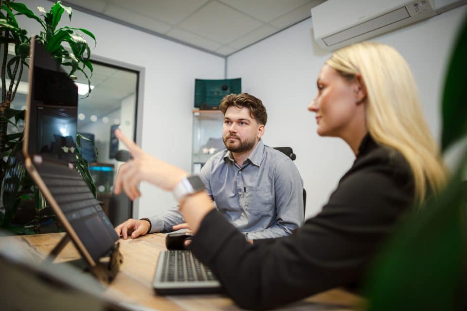 Workplace Strategy Coaching session showing a coach and participant reviewing a digital workspace together, focusing on strategic ways of working and effective use of technology.