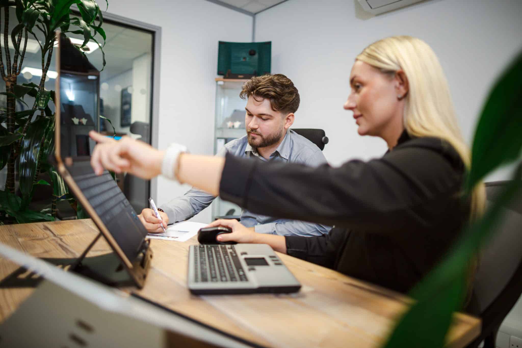 Remtek promotional image showing a workplace consultation in progress, with team members reviewing a laptop based workstation and discussing ergonomic adjustments.