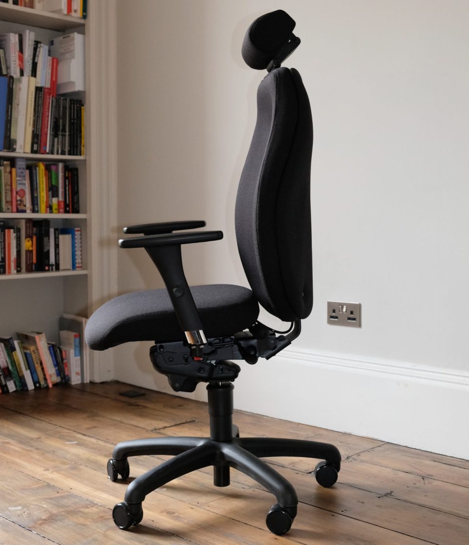 Ergochair Adapt 610 ergonomic chair, upholstered in black. image shows chair in a home setting, infront of a white bookcase