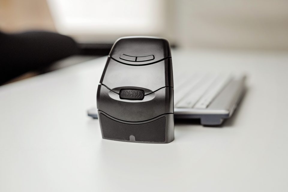 BakkerElkhuizen DXT3 Cordless Ergonomic Mouse set up on desk, close up of mouse in foreground with keyboard in background