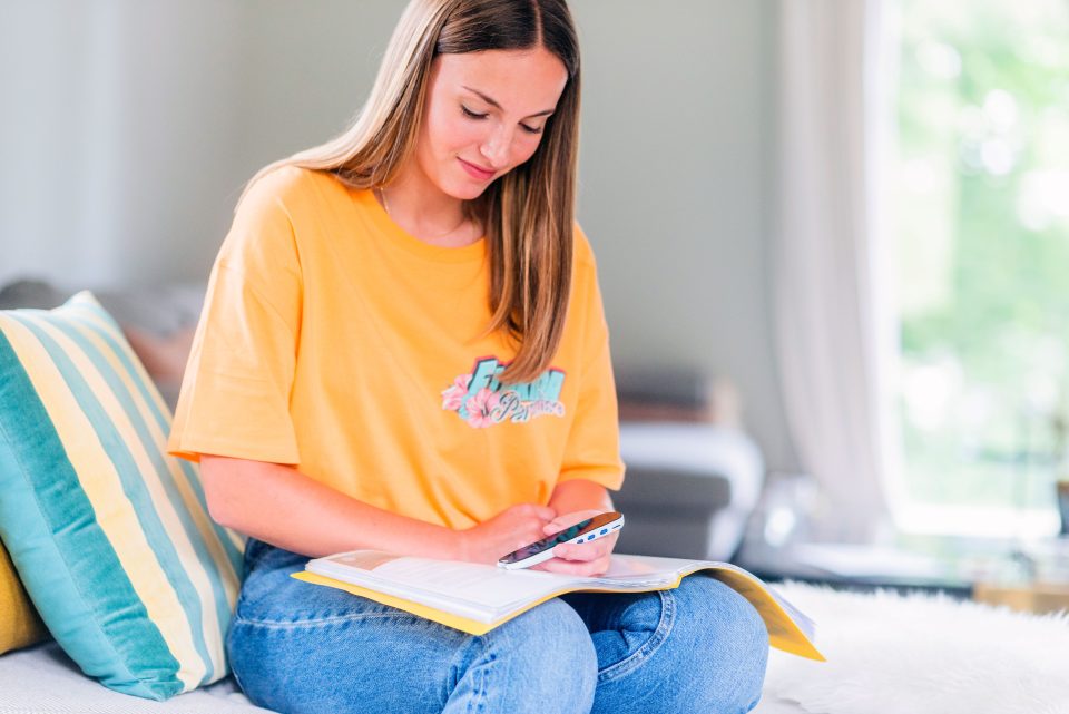 IRISPen Reader 8 in use by a woman on an open book which is resting on her knees.