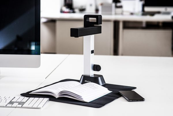 IRIScan Desk 6 set up on a white desk, scanning a book