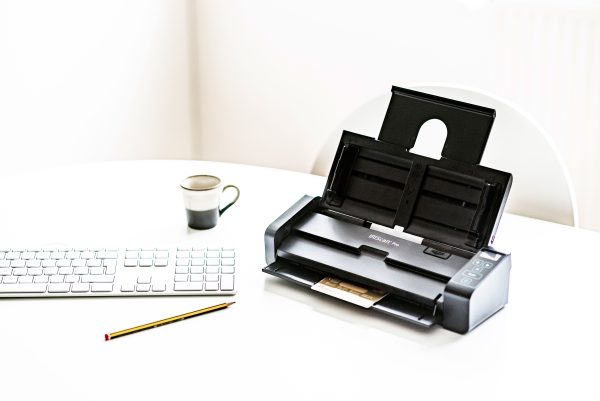 IRIScan Pro 5 on a white desk with keyboard, pencil and coffee cup