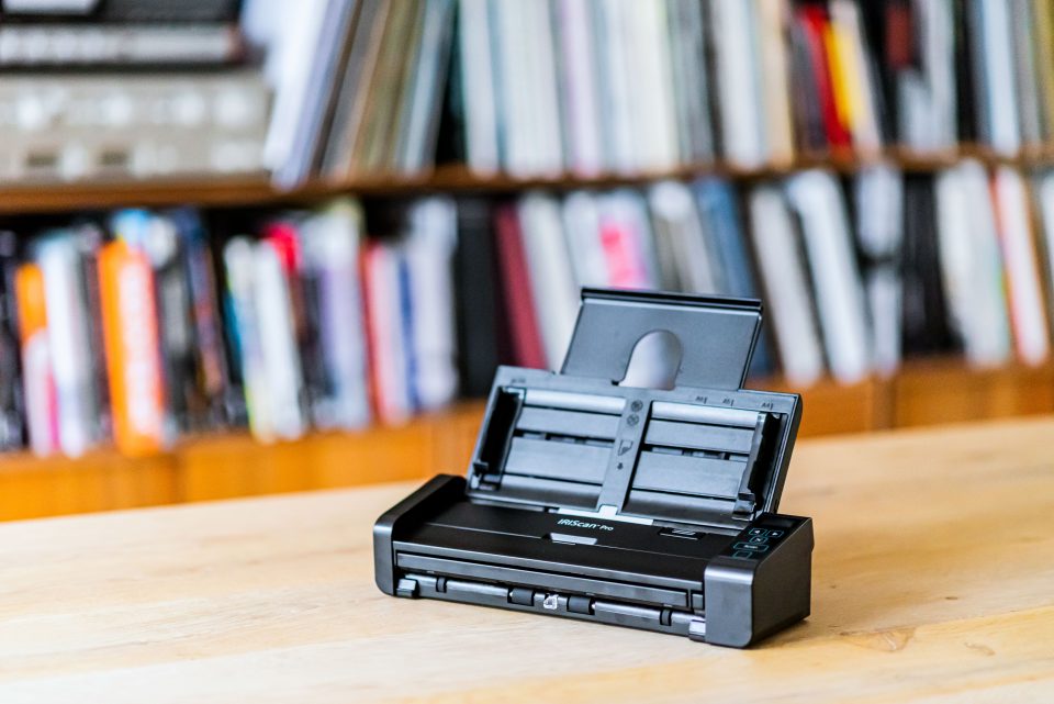 IRIScan Pro 5 on a brown desk with bookcases in the background