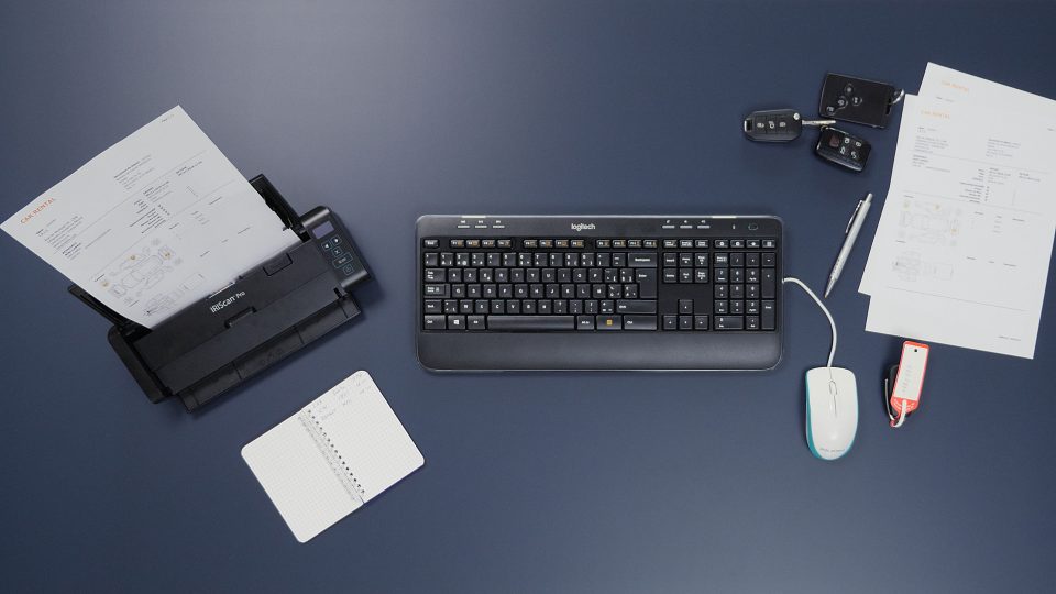 IRIScan Pro 5 on dark blue work surface, keyboard and mouse are in view