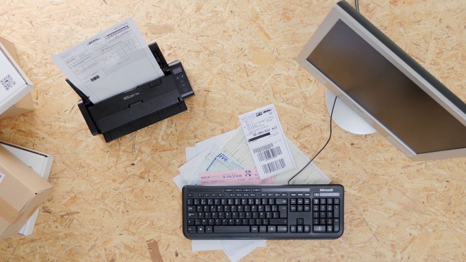 IRIScan Pro 5 on light brown work surface, keyboard and mouse are in view