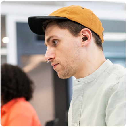 loop quiet 2 earplugs black in use by a man in a grey sweater, and a mustard cap