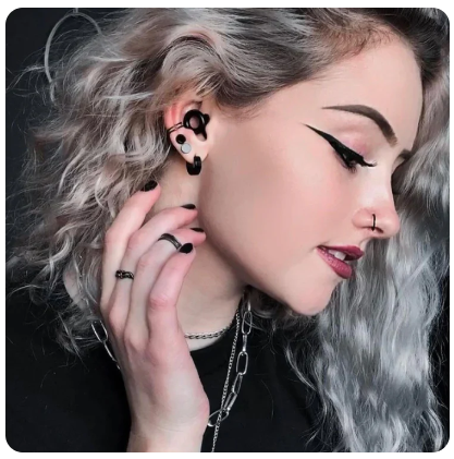 loop quiet 2 earplugs black in use by a woman with curly silver hair, stylised makeup and piercings.