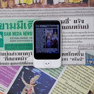 Pocketalk device in use converting a newspaper to another language