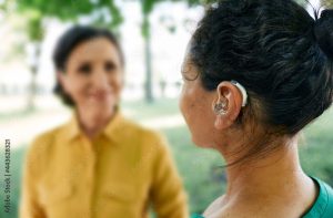 Hearing impairment support shown through a person wearing a hearing aid while engaging in conversation, representing assistive hearing technology and inclusive communication.
