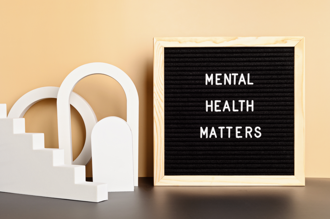Letter board displaying the words mental health matters next to abstract white shapes, set against a warm neutral background.