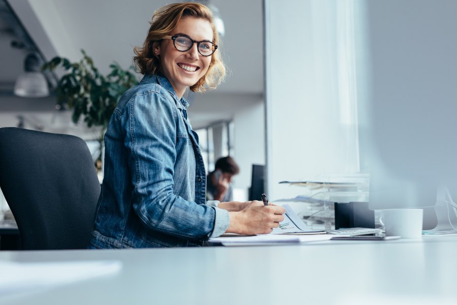 Smiling office worker sitting comfortably at a desk after completing a successful Display Screen Equipment (DSE) assessment.