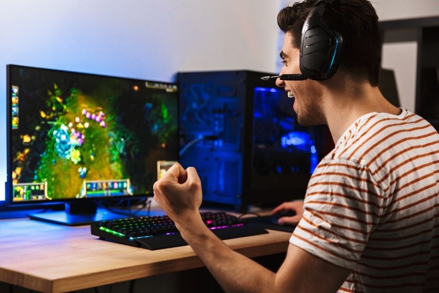 Gamer celebrating while playing on a PC, representing how choosing between wired vs wireless mice affects gaming performance.