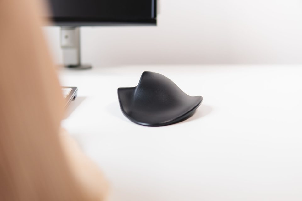 Handshoe Mouse Cordless ergonomic vertical mouse resting on desk with curved shape designed for natural hand positioning