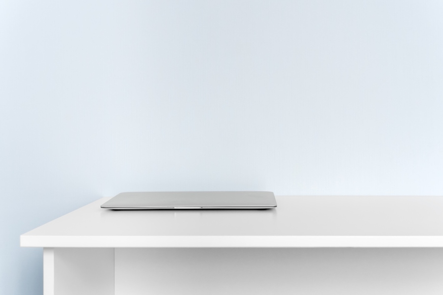 Minimal desk with a closed laptop, illustrating available workspace and surface area for a desk converter.