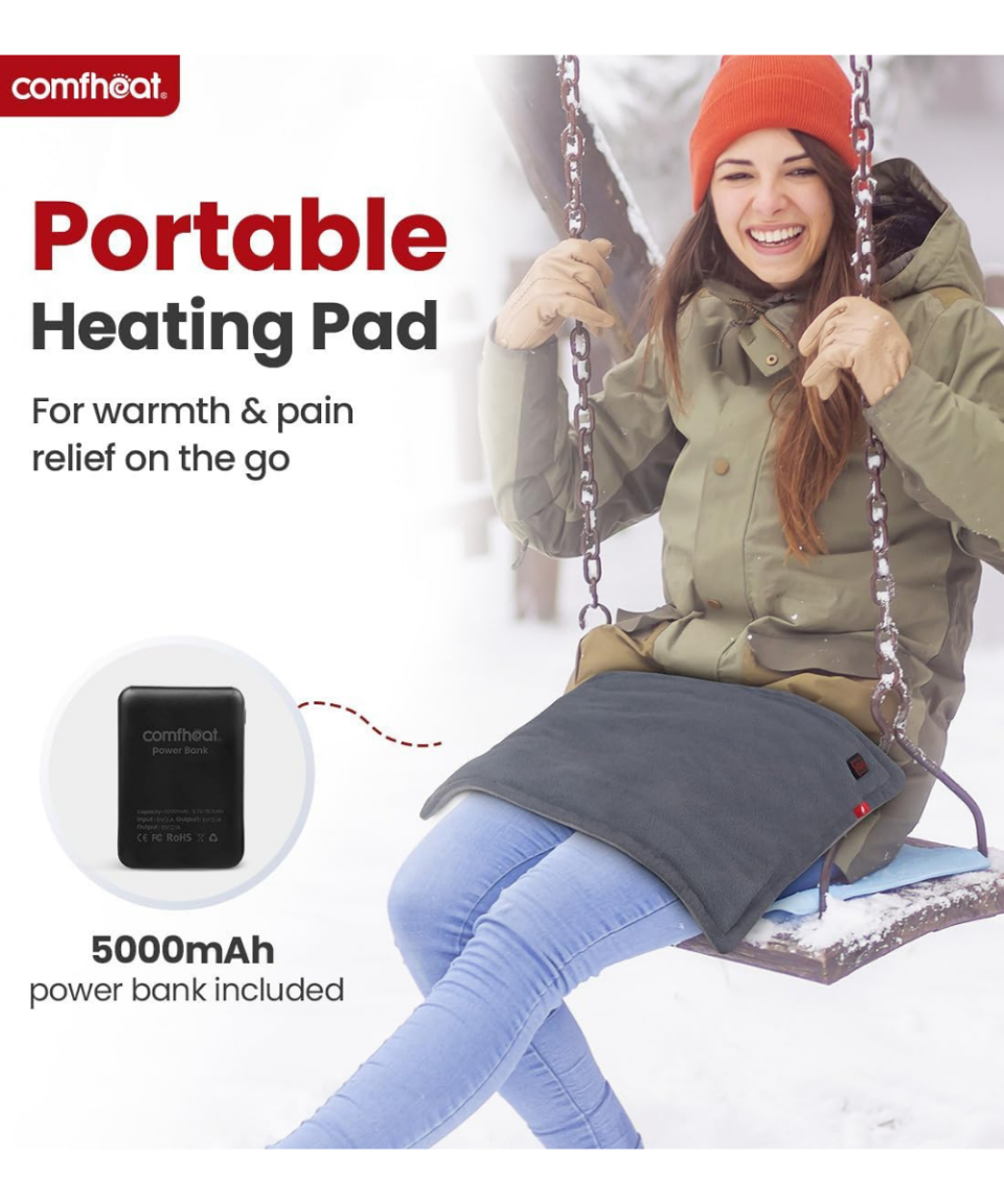 Comfheat Rechargeable Heating Pad being used across a person's lap outdoors with the included portable power bank. 1