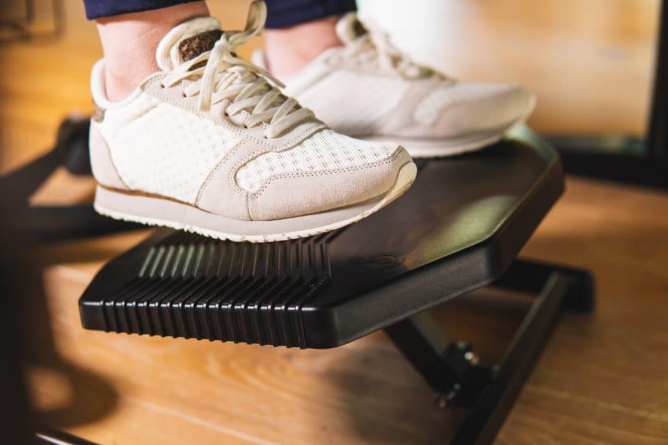 Person using the Basic950 BakkerElkhuizen footrest while wearing trainers.