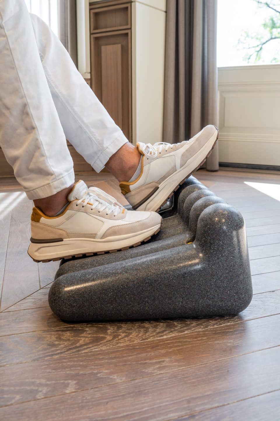 Person using the FootRest No.4 by BakkerElkhuizen while wearing trainers.