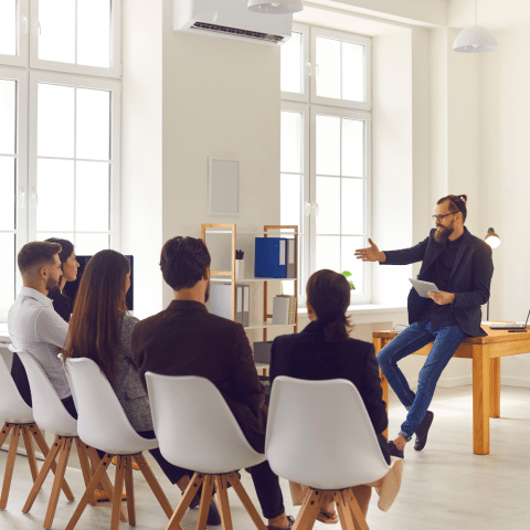 Training session with a presenter speaking to employees in a bright workplace.